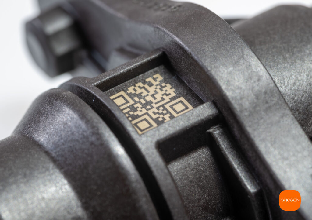 Just-in-Time (JIT) Laserbeschriftung von Kunststoff (PA), schwarz. Weißumschlag von schwarzem PA Kunststoff. An einer unzugägnlichen Stelle wurde ein QR Code mit dem Laser aufgebracht.