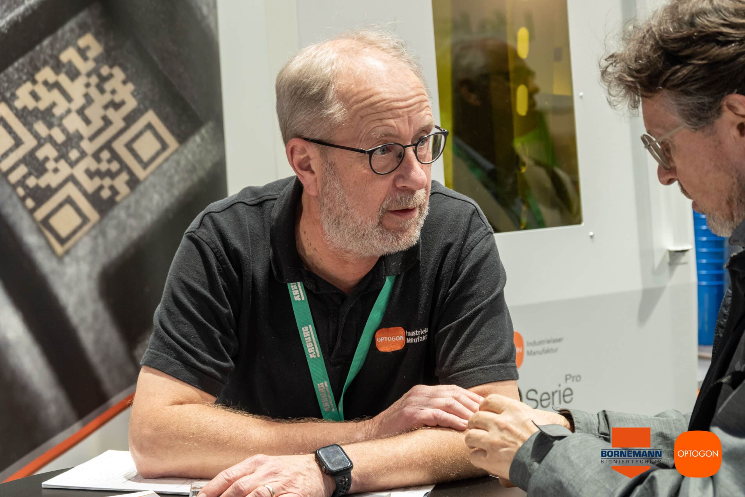 Andreas Plauschin im Gespräch mit einem Messebesucher auf dem OPTOGON-Stand.