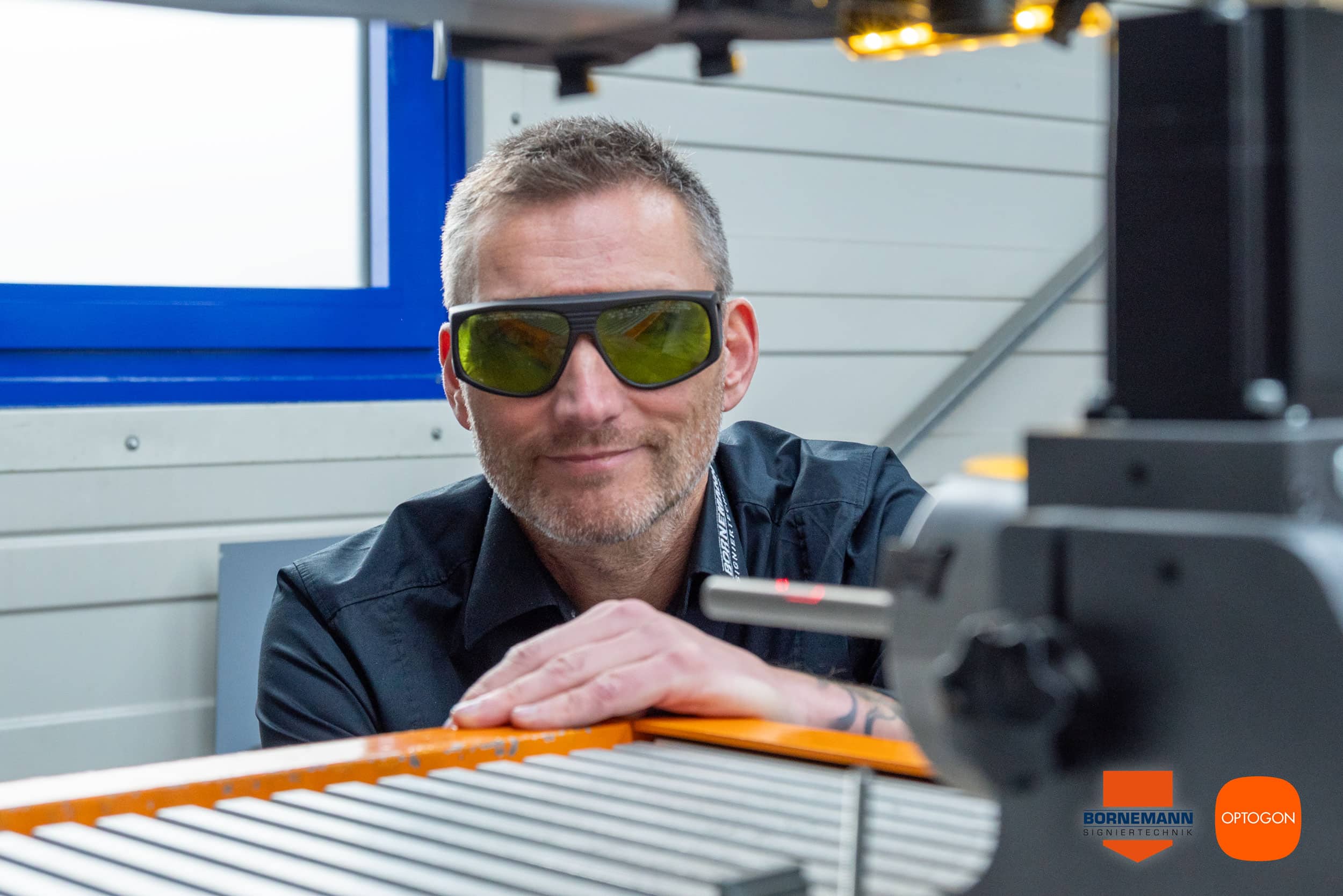 Roland Wilhelm arbeitet im Laserschutzraum von Bornemann am offenen OPTOGON-Lasersystem und trägt eine Schutzbrille für Laserschutzklasse 4.