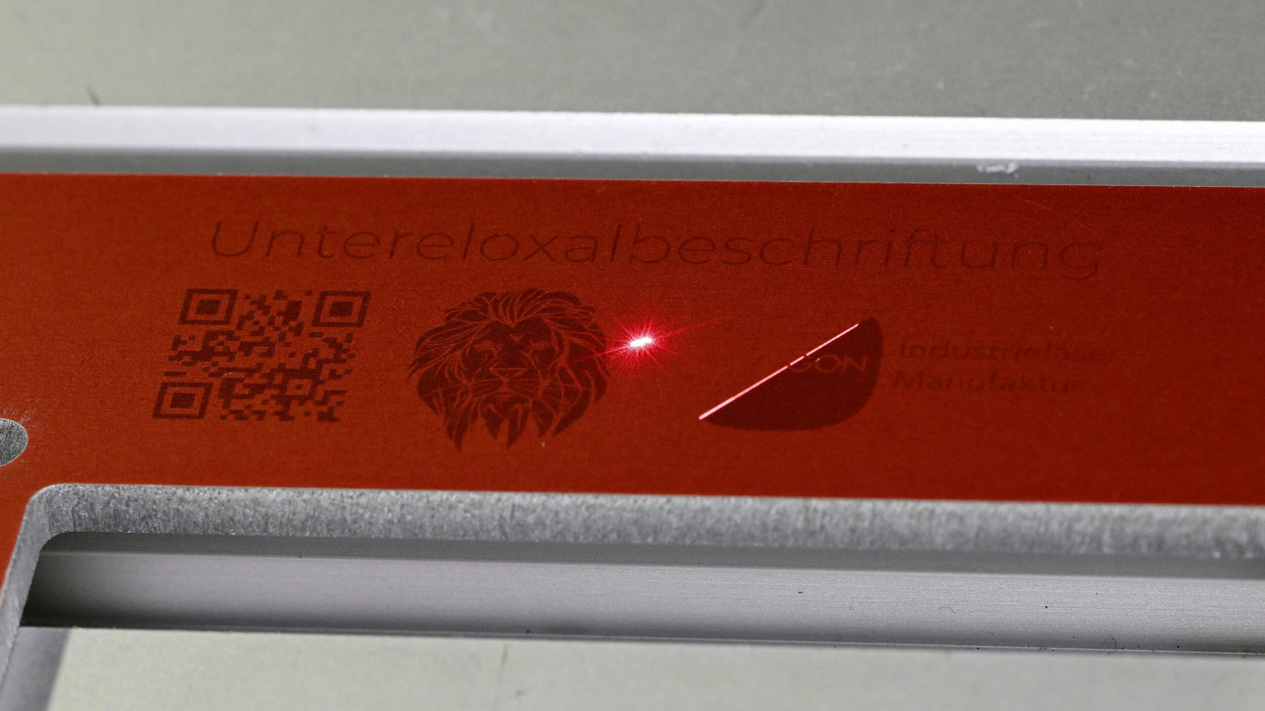 Laserprozess zur Untereloxalbeschriftung auf rot eloxiertem Aluminium bei OPTOGON